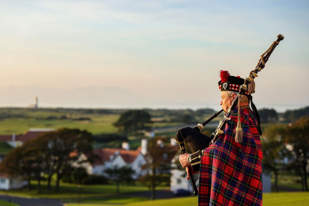 A piper playing the bagpipes at sunset