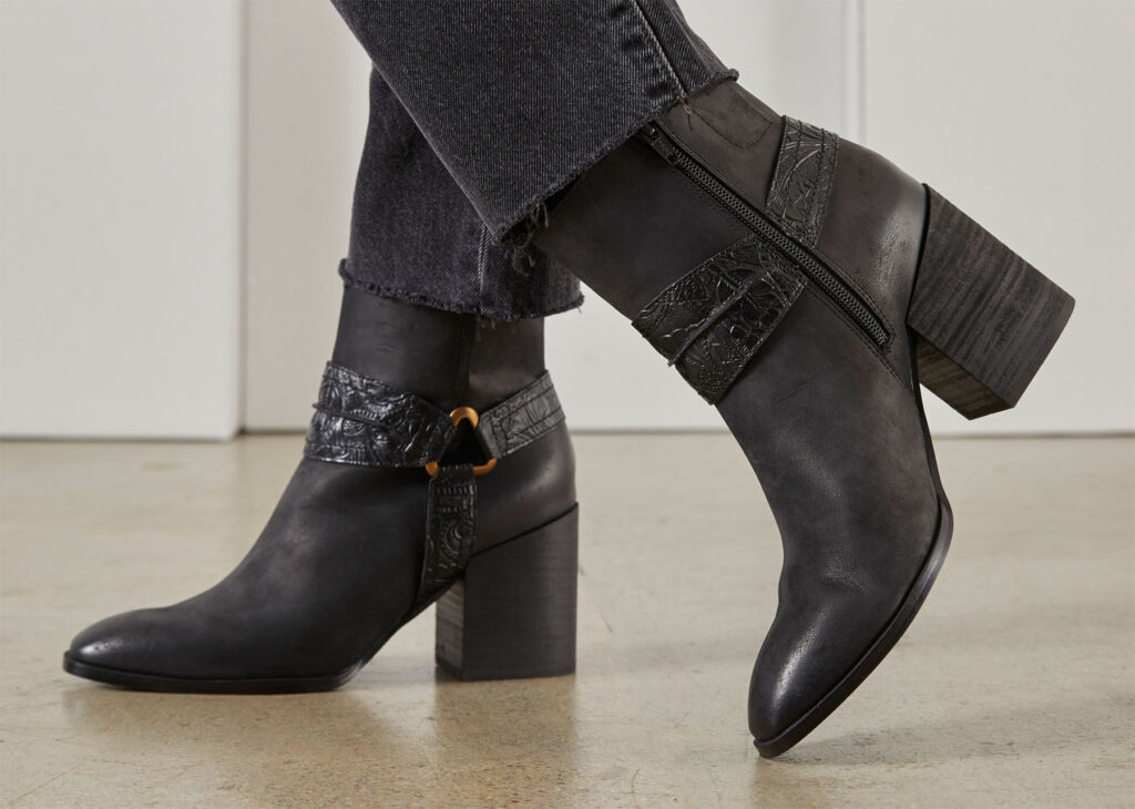 A side profile look at a pair of black boots being worn
