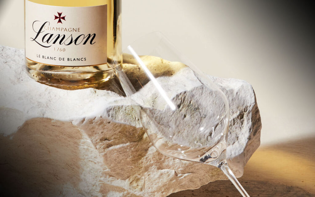 A bottle on a rock with a champagne flute tilted towards it