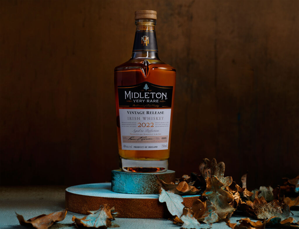 A bottle of the whiskey on a plinth surrounded by fallen leaves