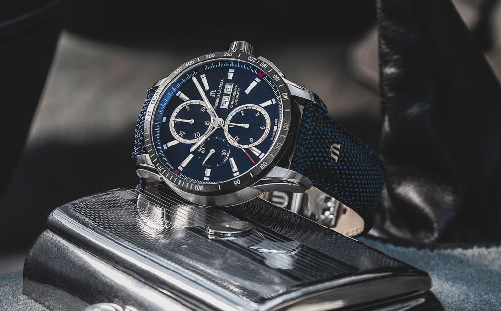The new model watch with a blue face on the carpet inside a car footwell