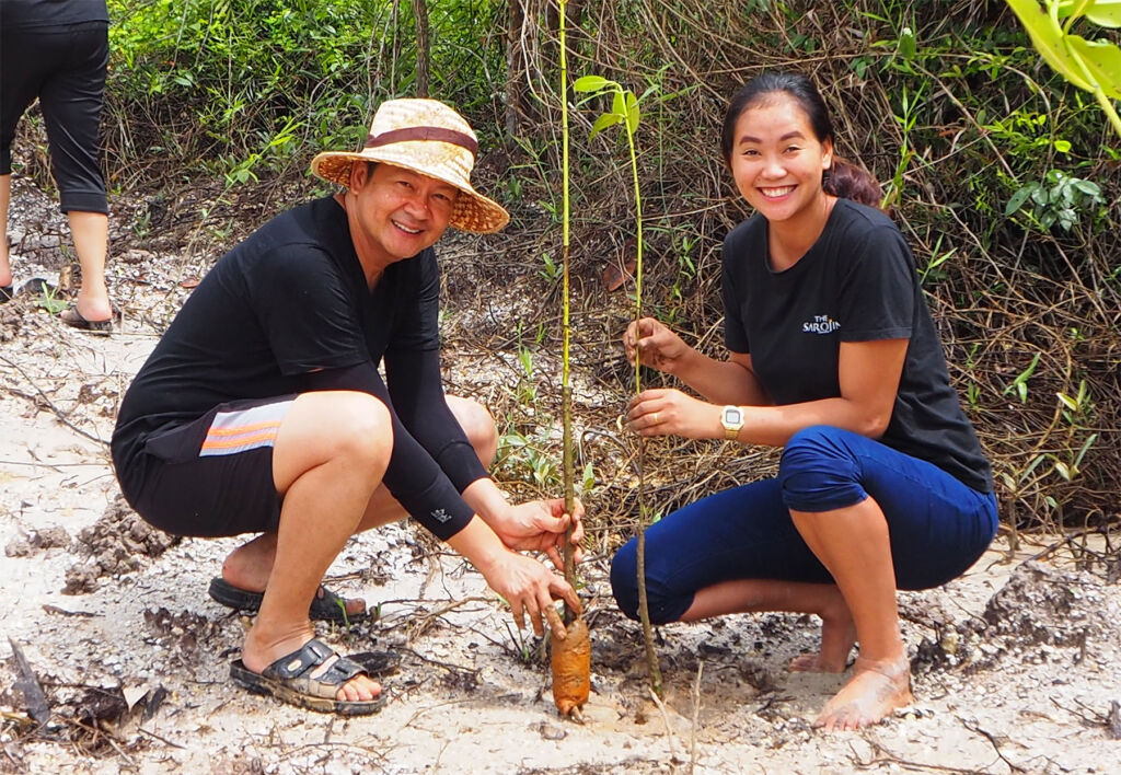 Two members of The Sarojin's Staff planting mangrove trees in Thailand