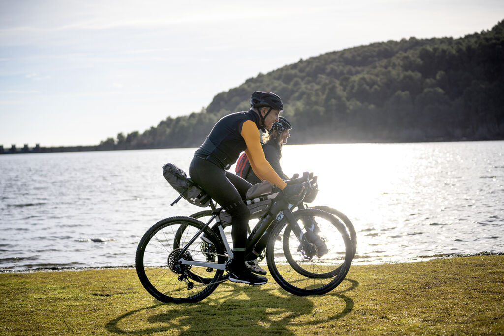 People riding the GRAVITAL e-bikes by a lake