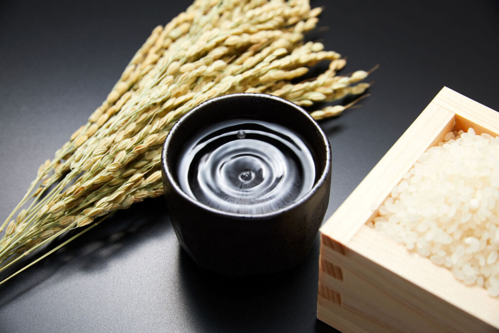 A cup of sake next to rice and grain