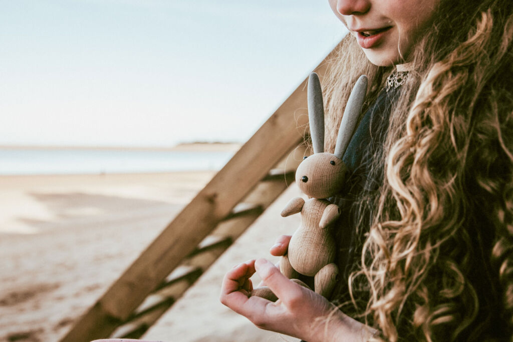 A young girl holding the limited edition wooden rabbit on the sea shore