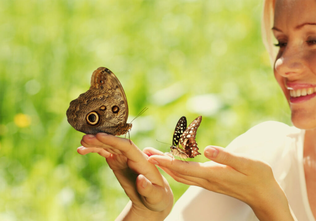 A happy and peaceful woman with butterflies landing on her hand