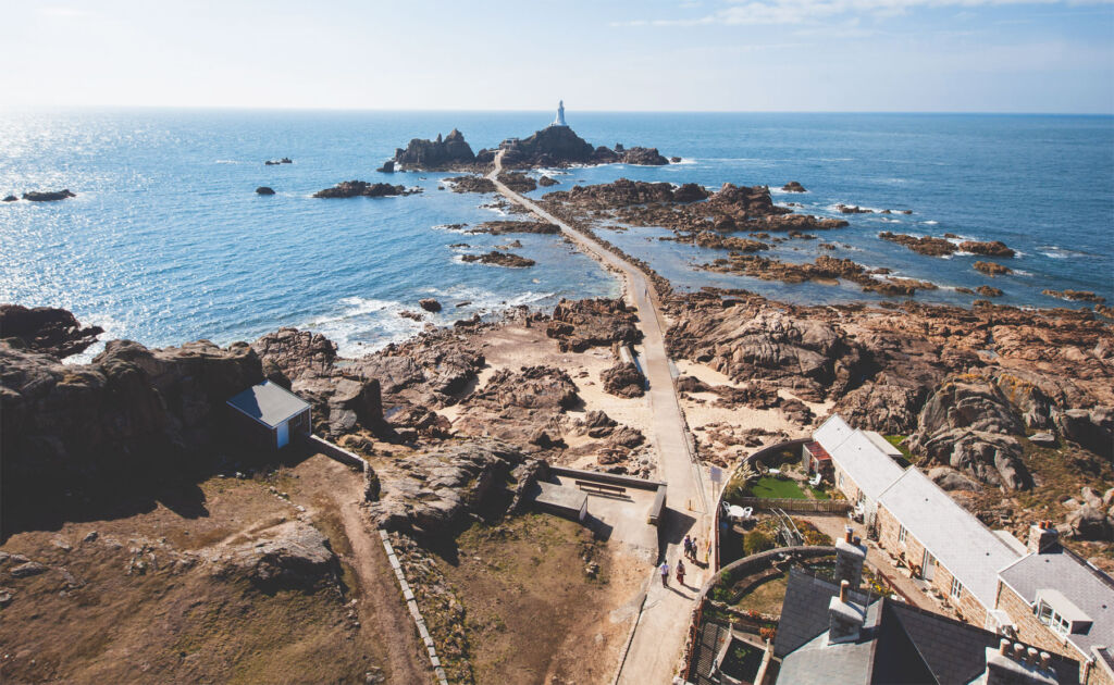 An aerial view of people walking towards the lighthouse