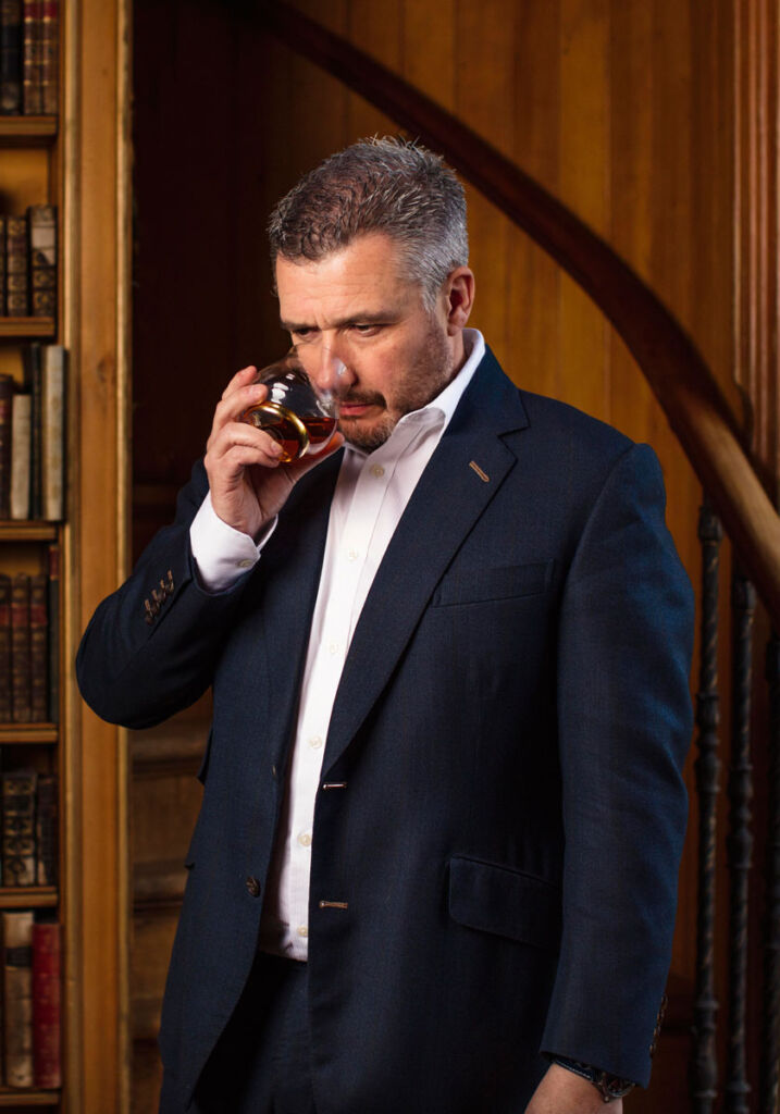 The master blender examining one of his whiskies in a library