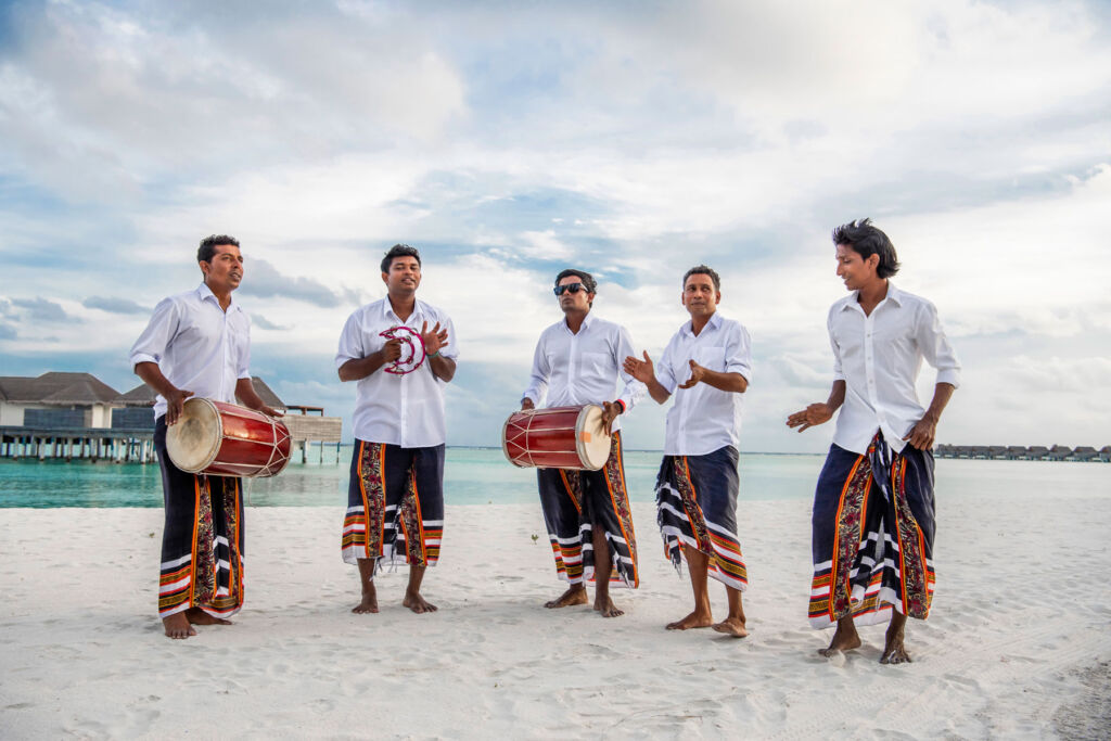 A five piece band on the beach playing traditional instruments