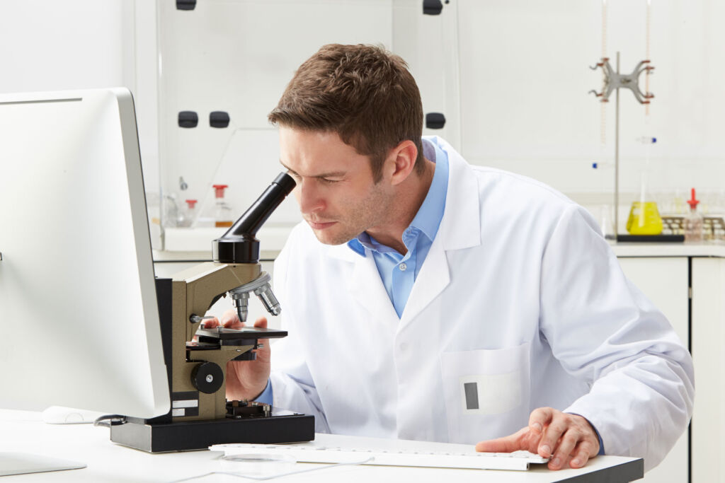 A male scientist examining something using a microscope