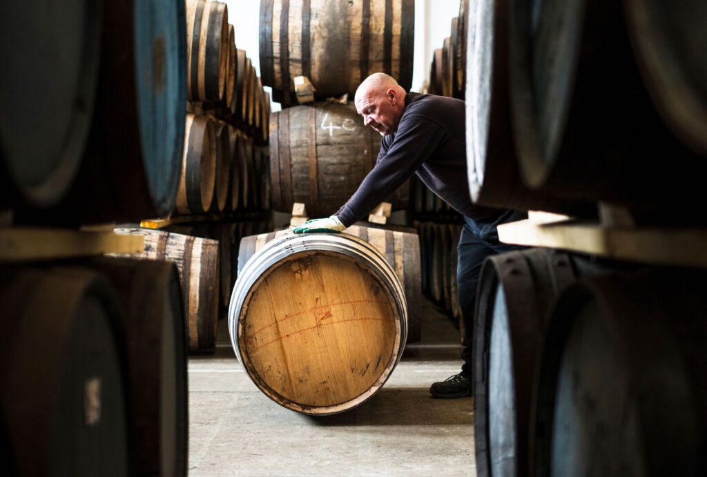A man rolling out a barrel at Holyrood Distillery