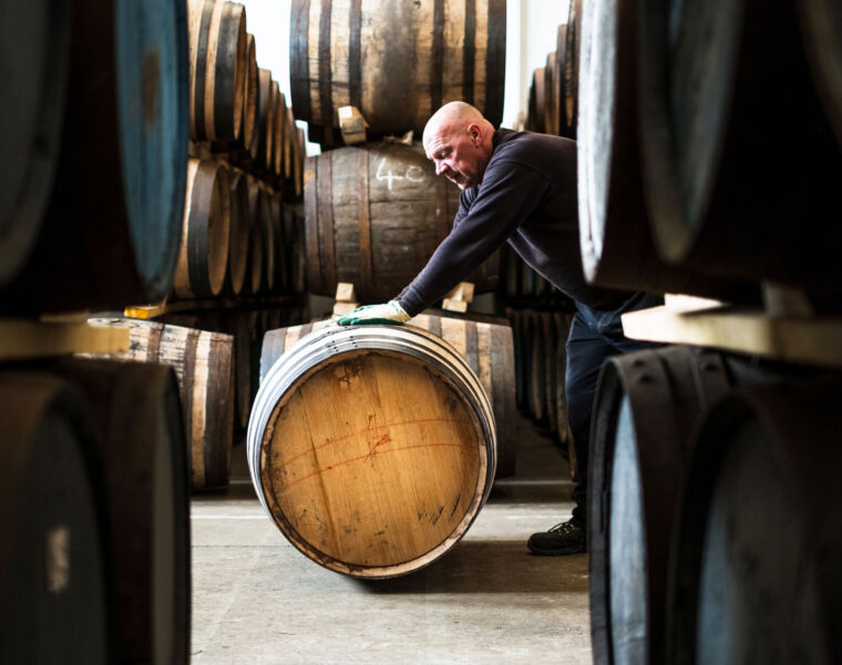 A man rolling out a barrel at Holyrood Distillery