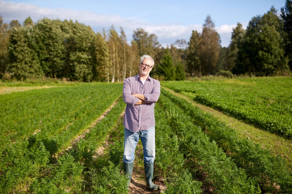 A farmer standing in a field with his arms crossed