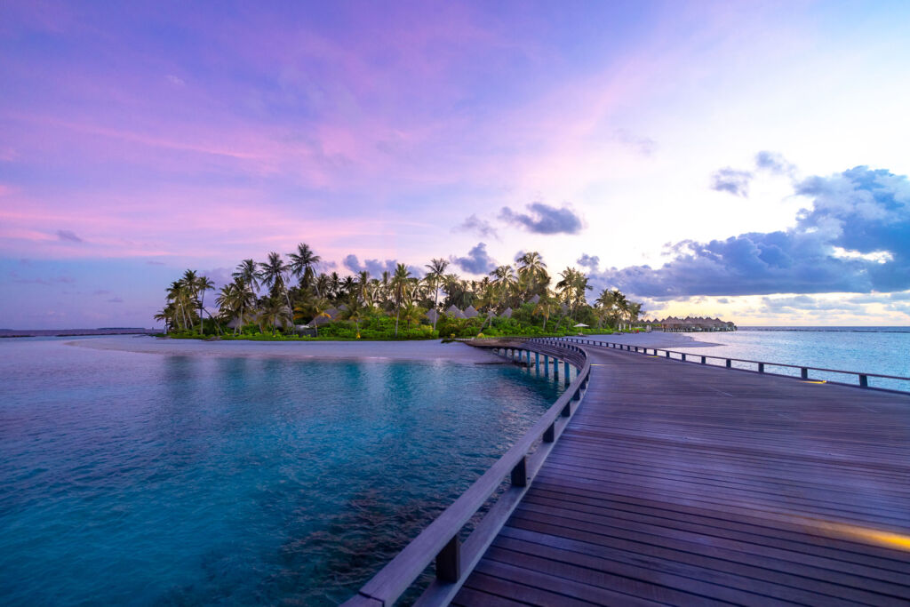 The overwater wooden walkway leading into the resort at sunset