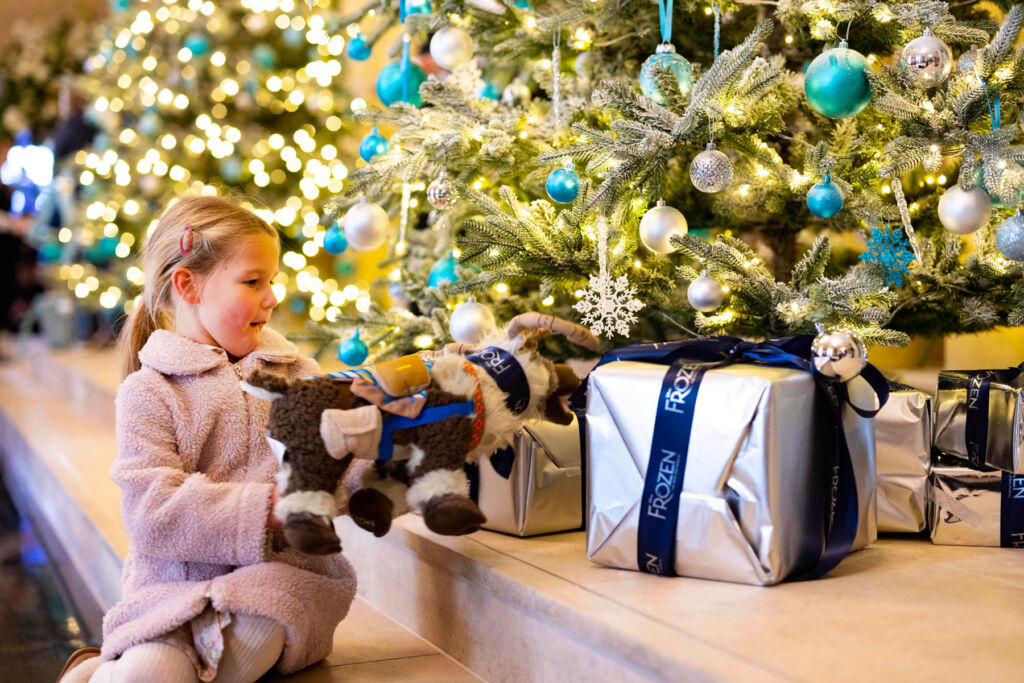 A young child touching a gift under the Christmas tree