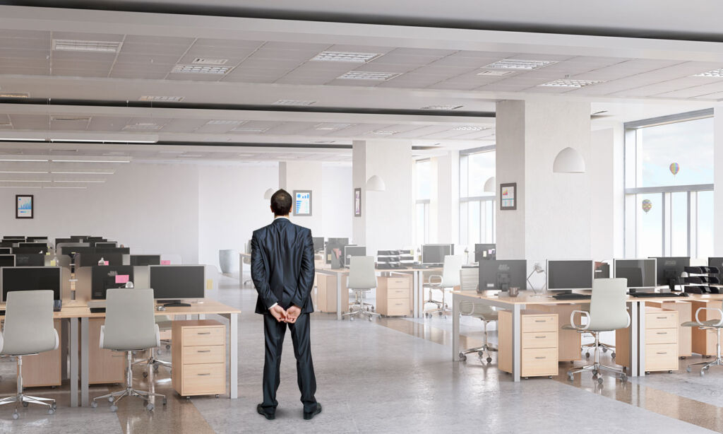 A man with his hands behind his back in an empty office
