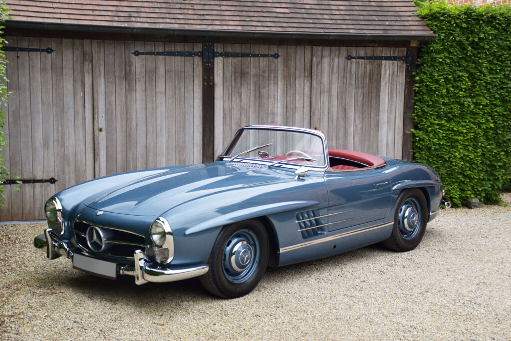 The 1958 blue Mercedes-Benz 300 SL parked outside a wooden garage