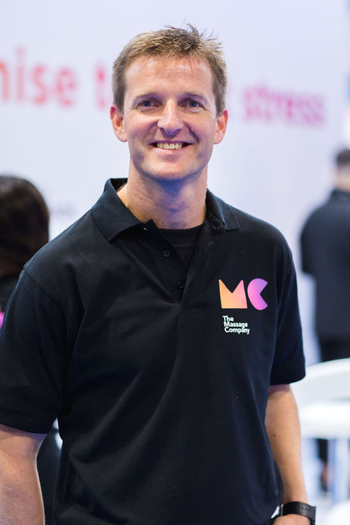 A smiling Charlie Thompson wearing a black t-shirt emblazoned with the company logo