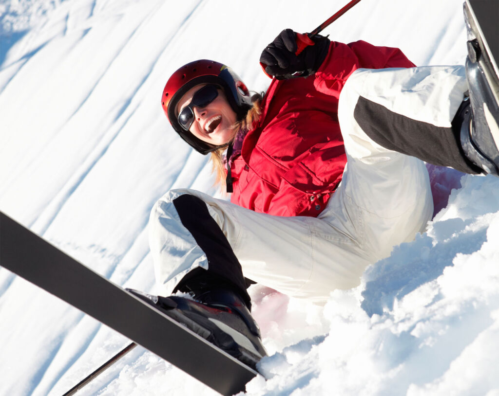 A woman falling over while skiing