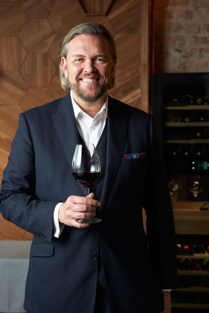 A smiling Andreas Larsson with a glass of red wine in his hand