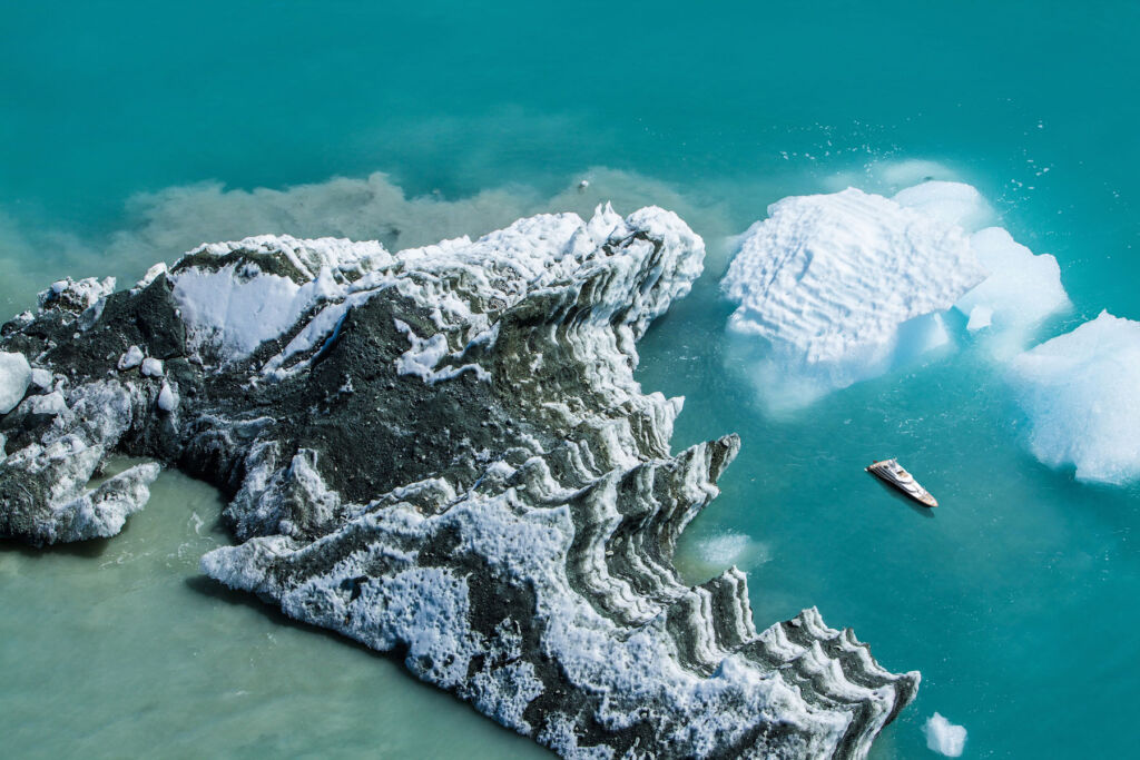 An aerial view of a large boat moored next to some icebergs