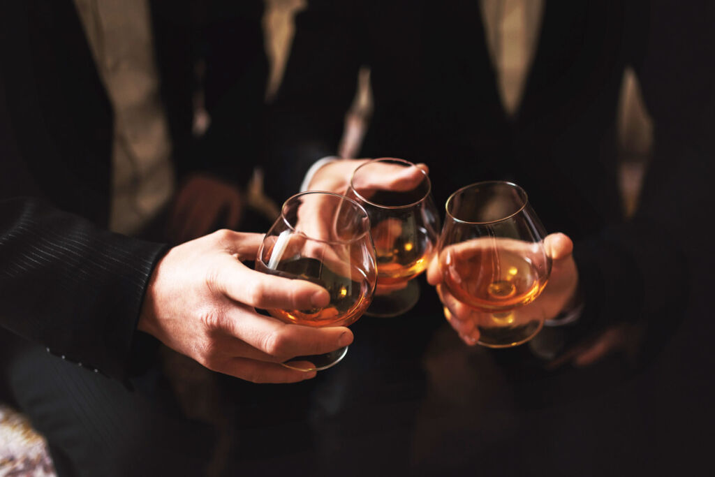 Three men making a toast with drams of whisky