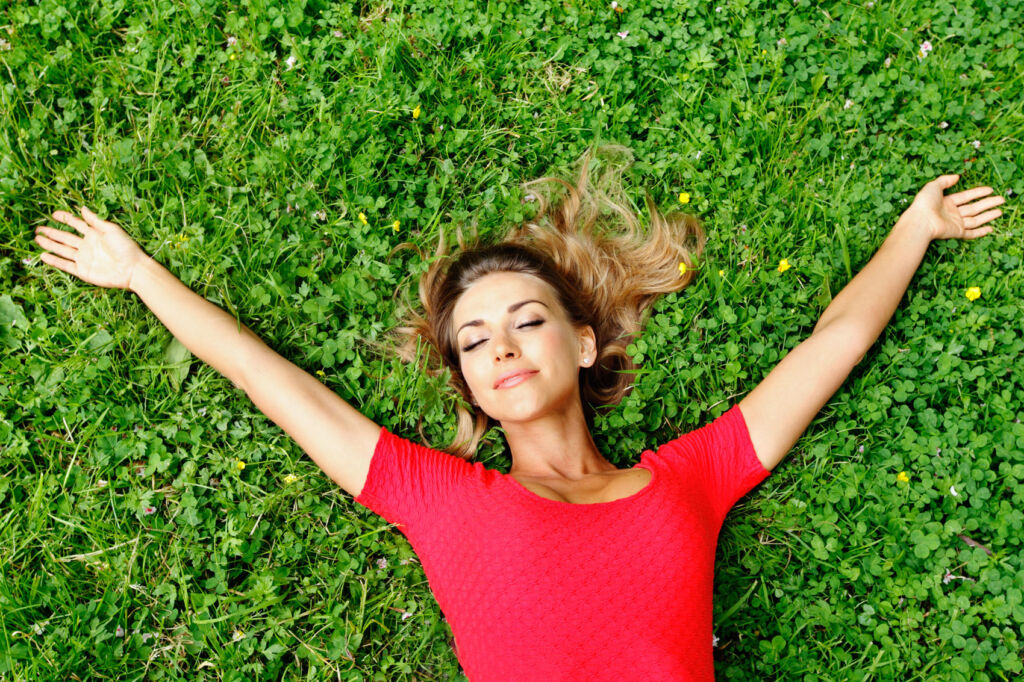 A stress-free woman laying on her back on the grass