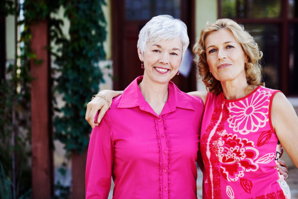 Two happy older ladies wearing bright pink tops