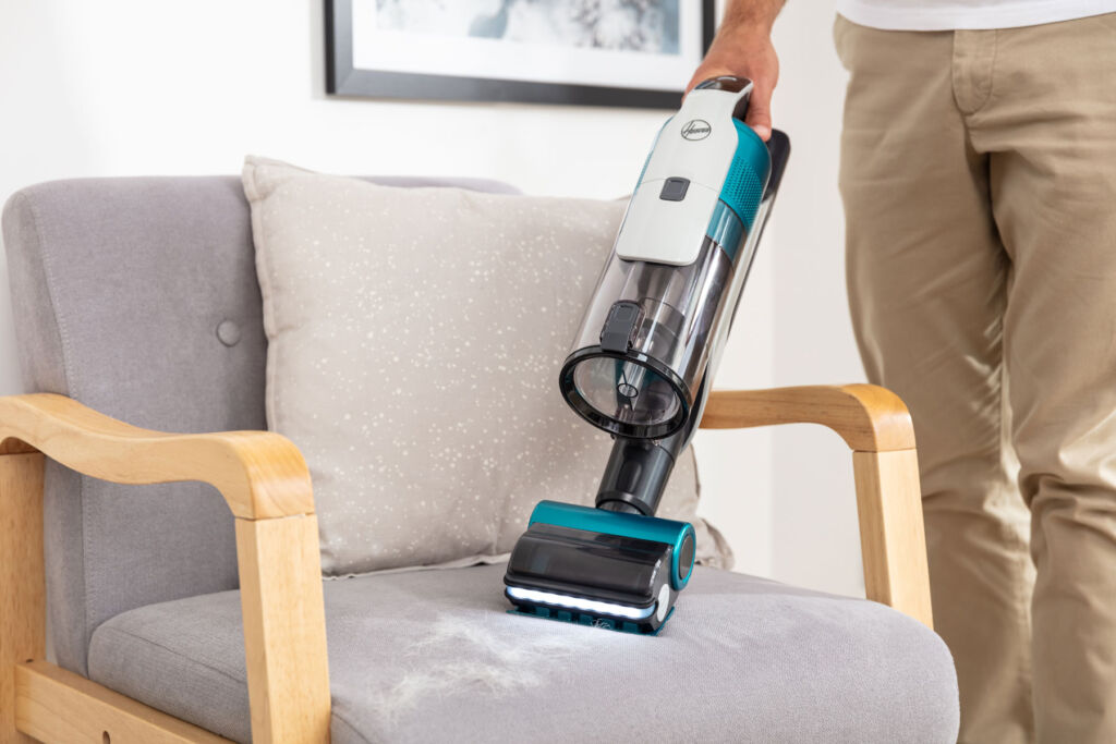 The vacuum being used to clean a chair in handheld mode