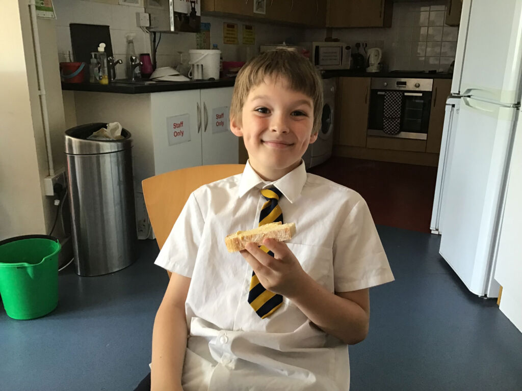 A very proud boy holding the sandwich he has just made