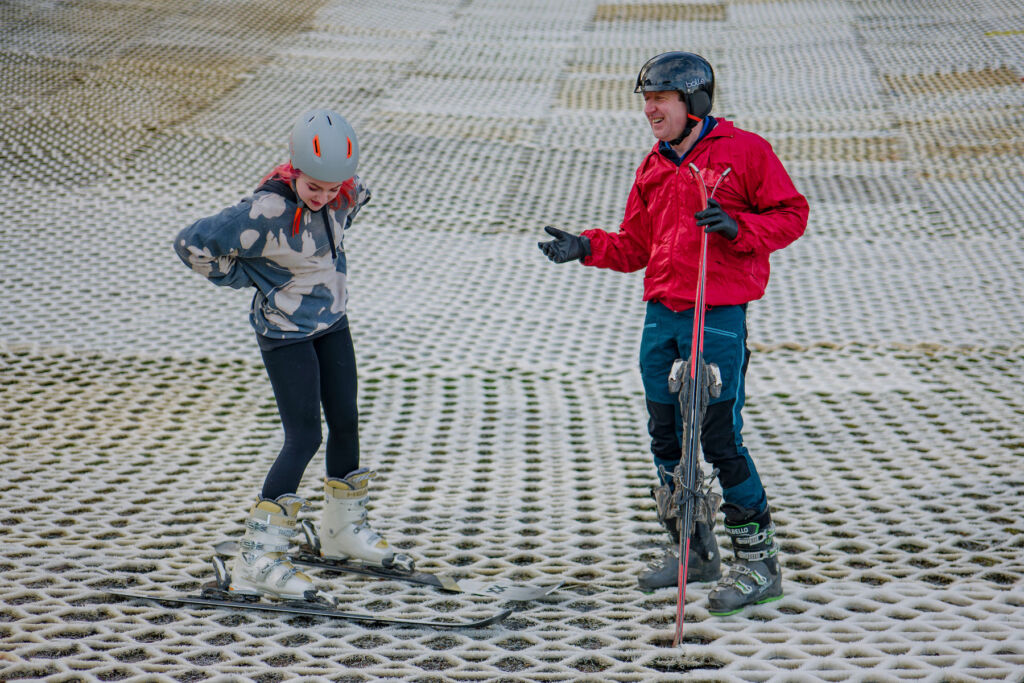 Martin teaching a young girl how to ski on a dry slope