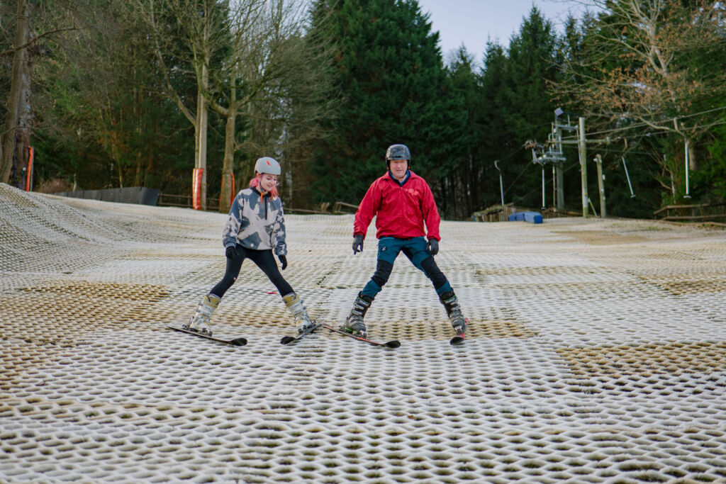 Martin skiing with a young girl down the dry slope