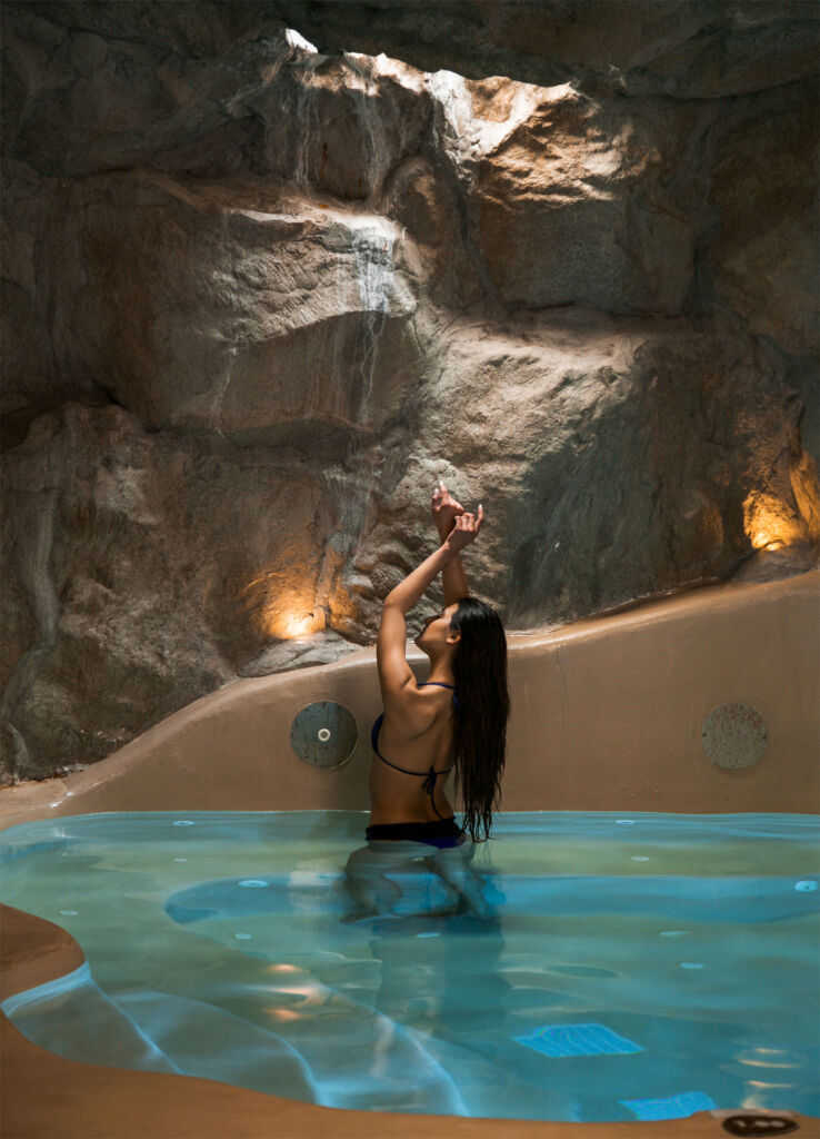 A woman in the pool in the cave spa with the sunlight coming through a gap in the natural rock ceiling