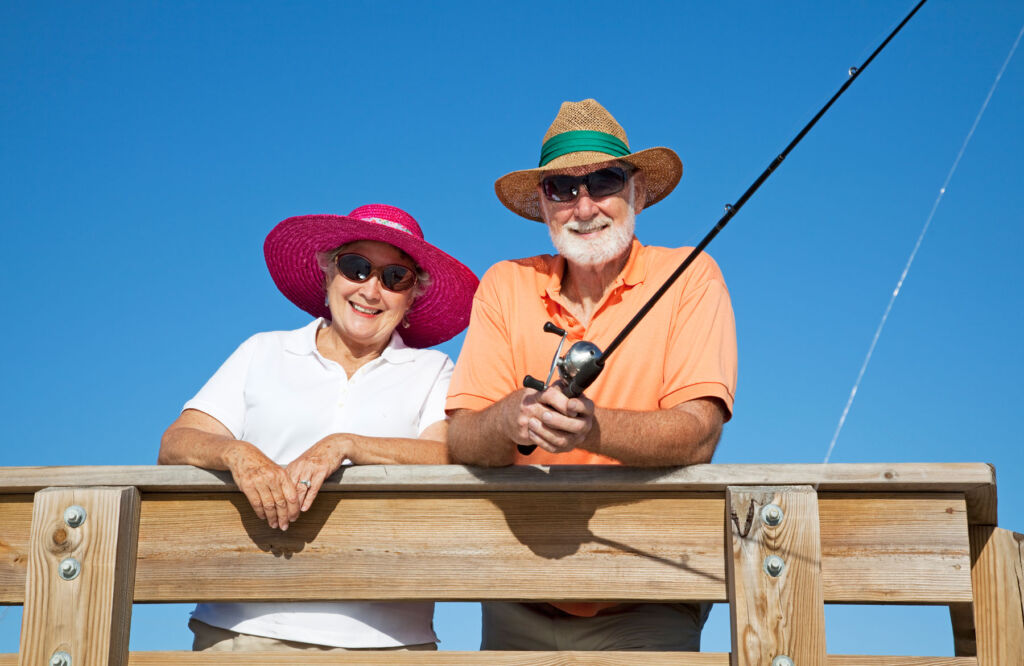 An elderly couple having fun fishing from a pier