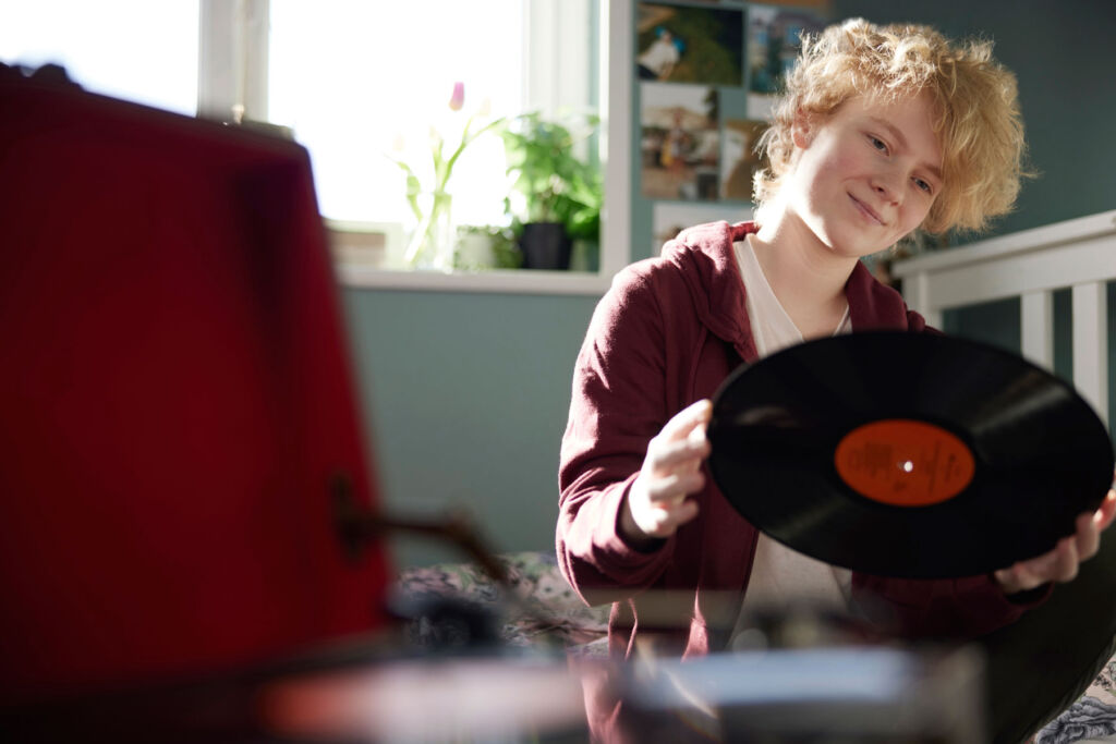 A young person placing a vinyl record on the player