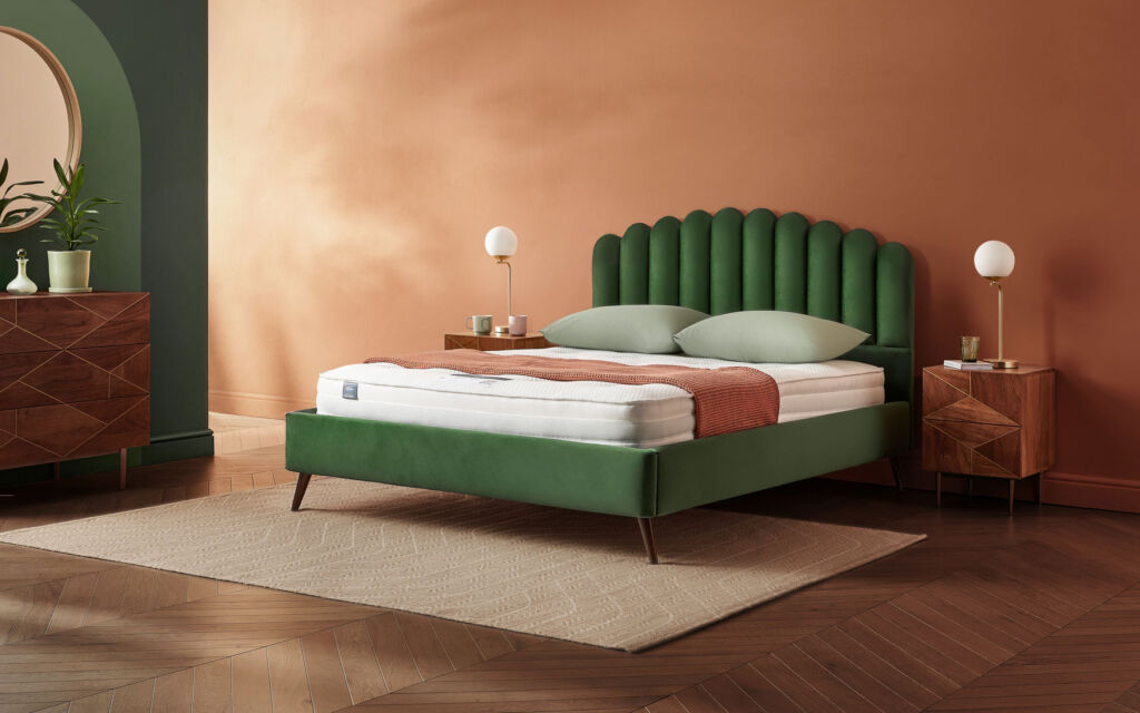 A green bed with scalloped fabric headboard in a room with green and light brown walls