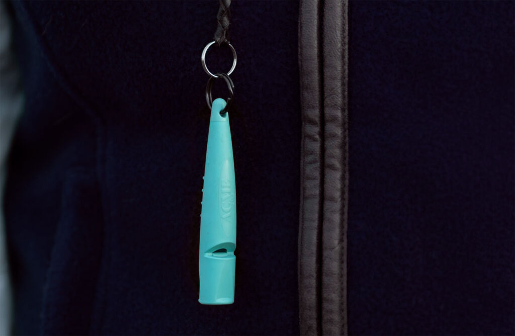 One of the new whistles in a turquoise colour attached to a jacket