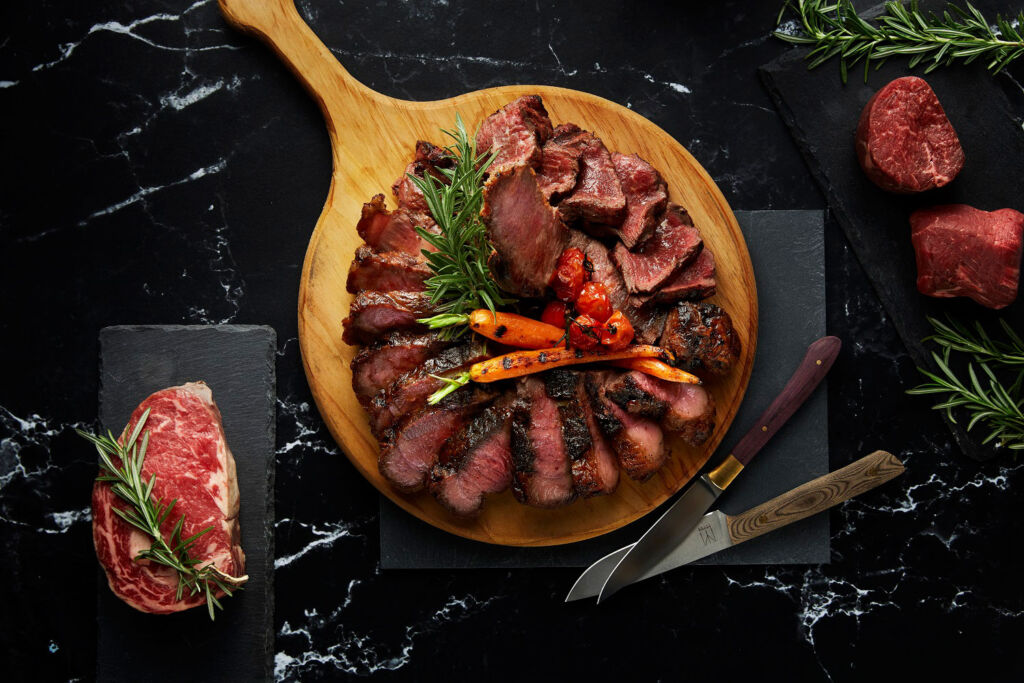 Sliced Angus T-bone steak on a wooden serving board