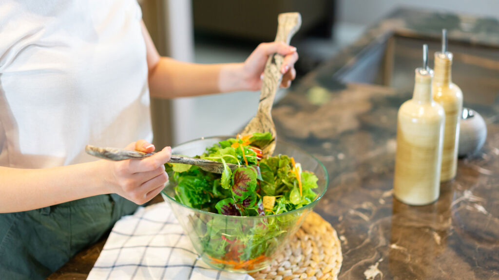 A woman making a health salad in a bowl