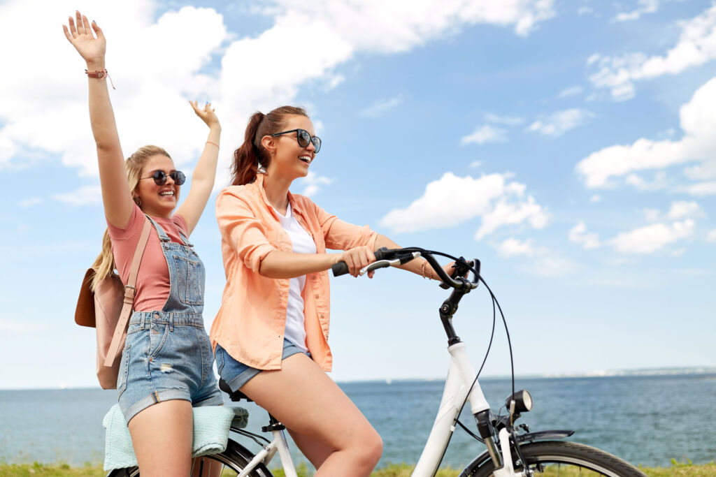 Teenage girls riding a bicycle by the beach