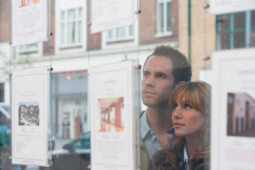 A couple looking at properties in an estate agents window