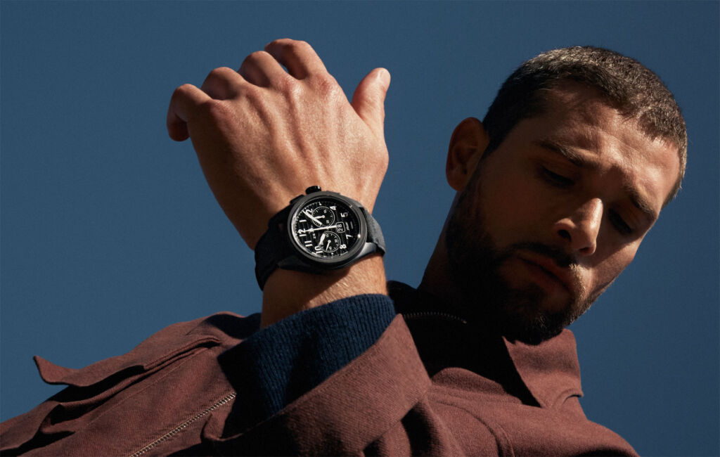 A bearded man wearing one of the new timepieces under a clear blue sky