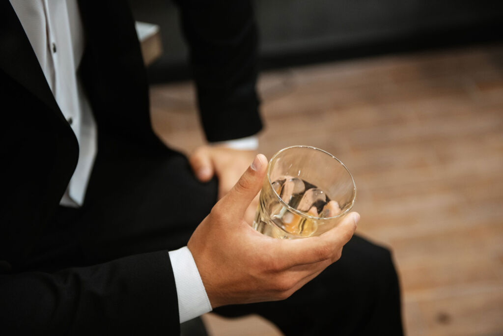 A man wearing a tuxedo holding a glass