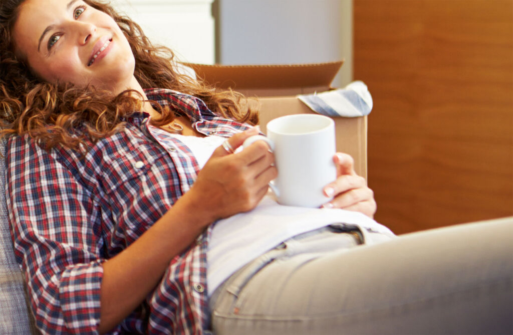 A woman relaxing on the sofa holding a cup of tea