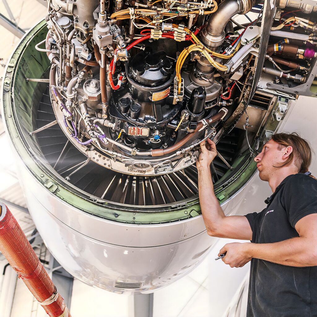 A company employee working on a jet engine