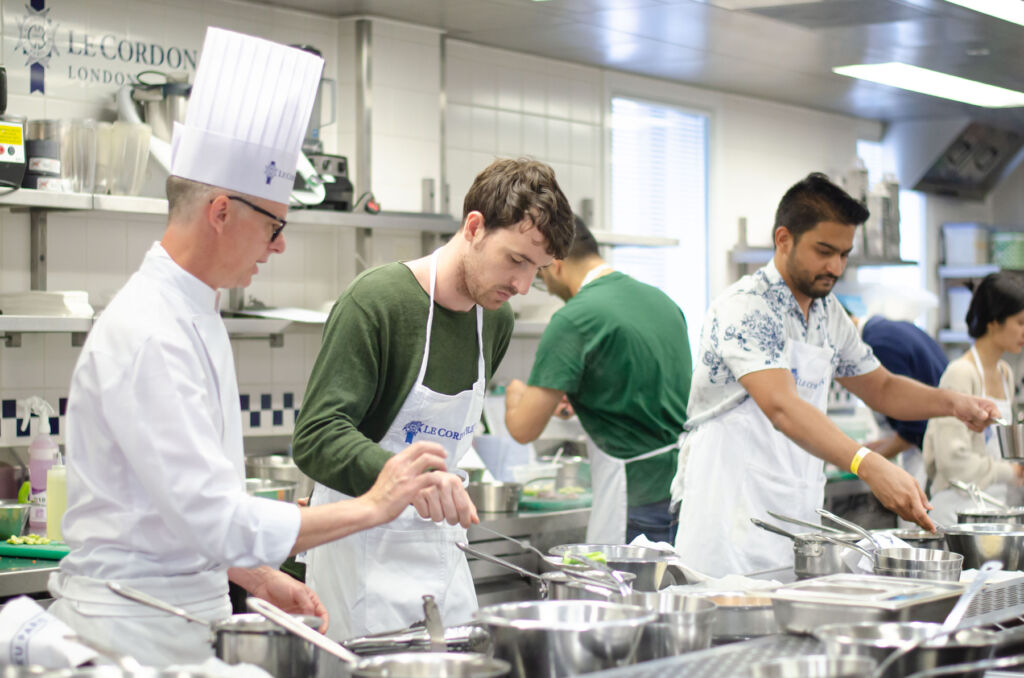 Amateur male chefs cooking in the kitchen with expert guidance