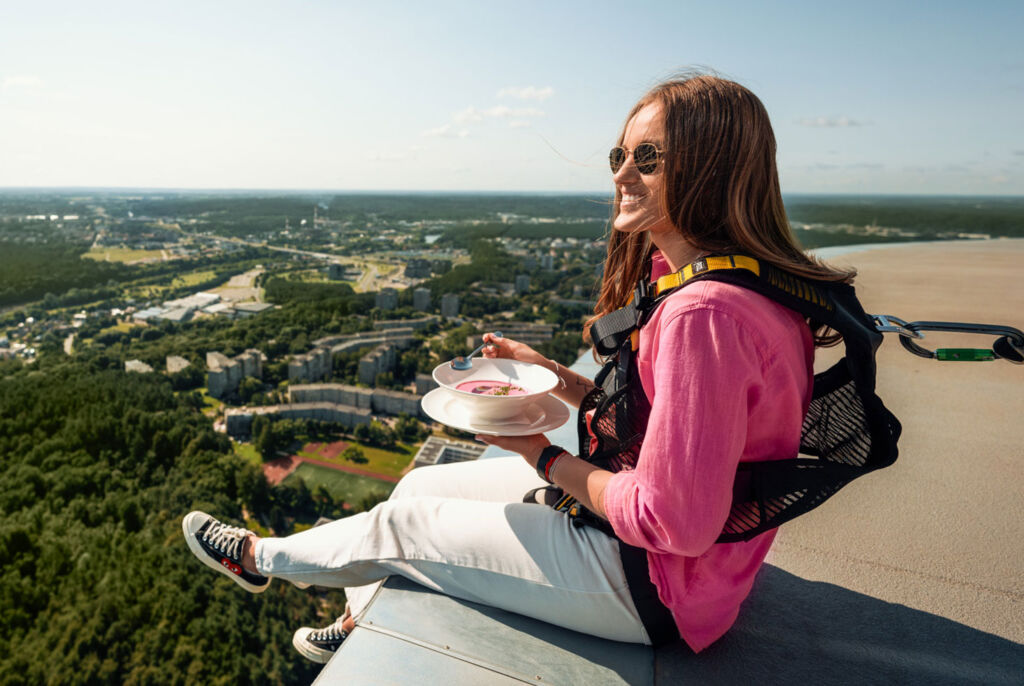 A young woman eating a bowl of soup on top of the city's TV tower