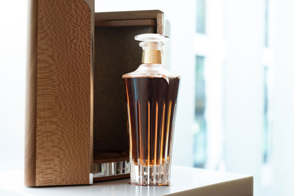 A decanter of the whiskey next to its open walnut case