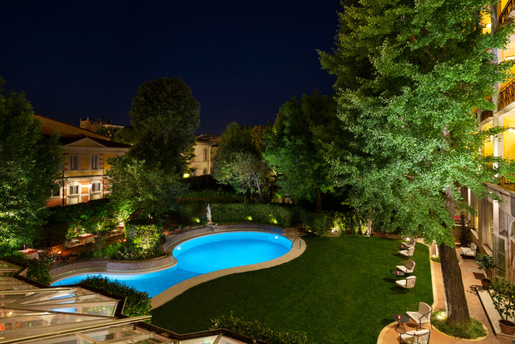 The brightly lit swimming pool and garden at night