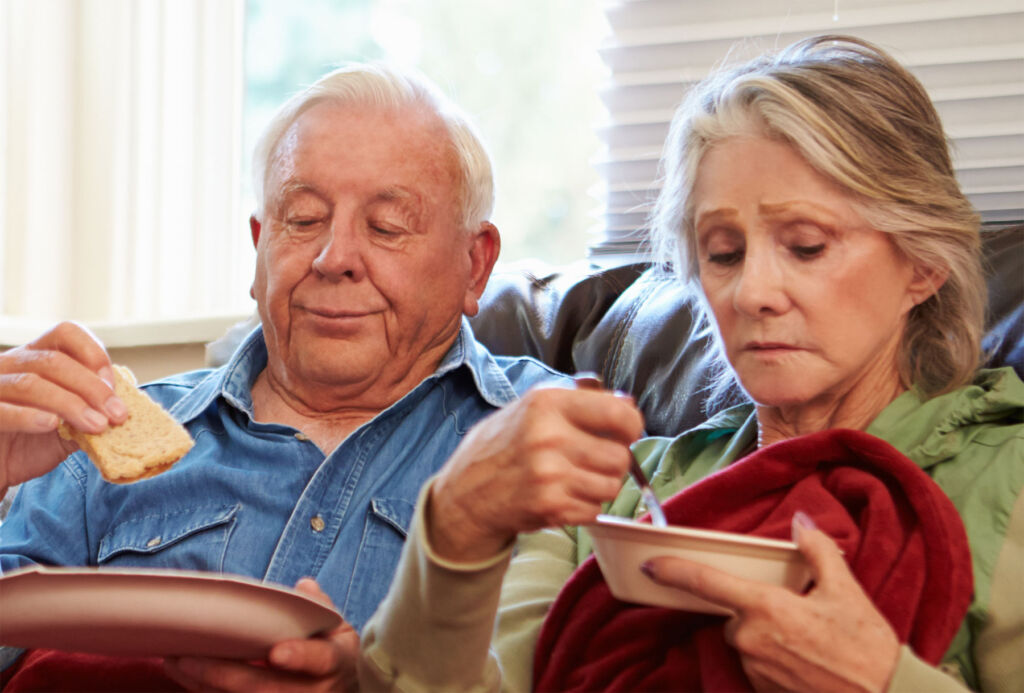 An older couple eating bread and soup